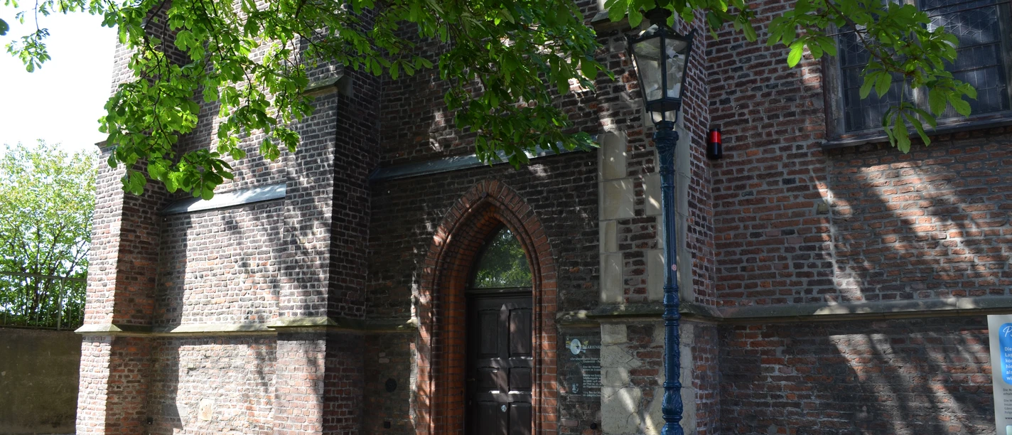 Marienkapelle in Monheim am Rhein Backsteinbau der Marienkapelle in Monheim am Rhein mit Spitzbogenportal und umgebender Straßenlaterne.