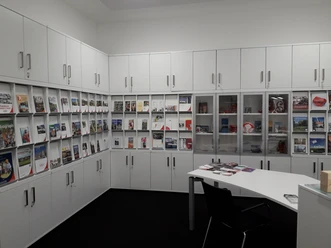 Tourist-Information Ratingen Reiseführer und Broschüren in einem Informationszentrum mit weißen Schränken und einem Tisch.