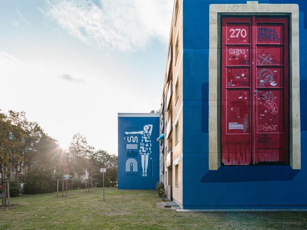 Arty Farty Gallery A colorful mural on a building shows a red door with graffiti and artistic elements.