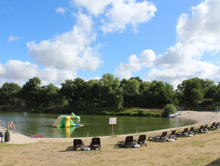 NaturFreibad Eystrup bietet klares Wasser, grüne Umgebung und Liegen entlang des Sandstrands.