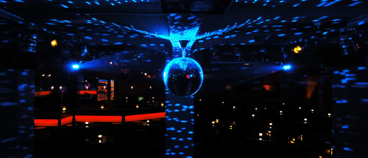 Au milieu de la salle du Spizz, une boule à facettes est éclairée par une lumière bleue ; danse à Leipzig, vie nocturne