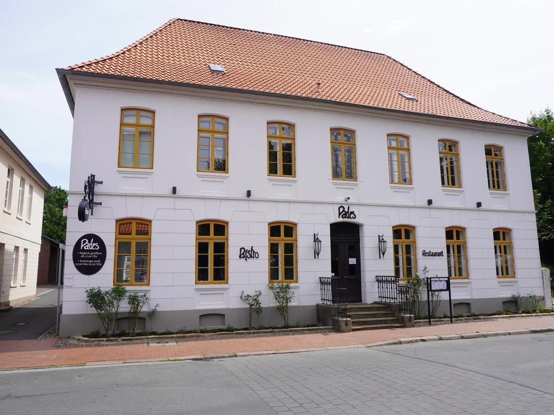 Pades Verden Ein historisches Gebäude mit weißer Fassade und gelben Fensterrahmen, benannt als Pades Verden.A historic building with a white façade and yellow window frames, known as Pades Verden.En historisk bygning med hvid facade og gule vinduesrammer, kendt som Pades Verden.Een historisch gebouw met een witte gevel en gele kozijnen, bekend als Pades Verden.