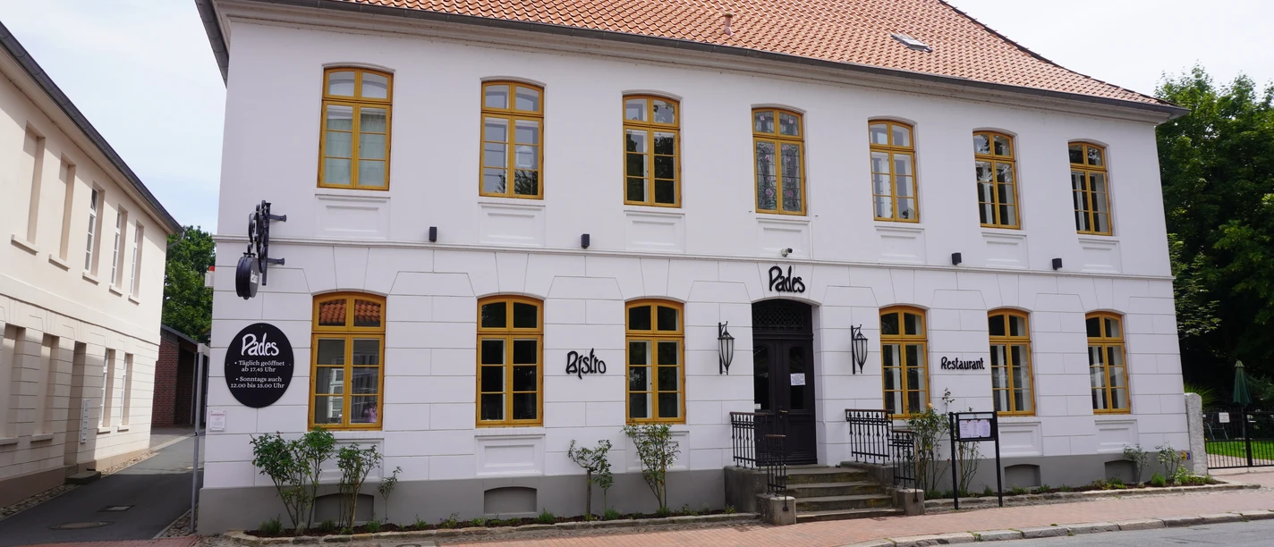 Pades Verden Ein historisches Gebäude mit weißer Fassade und gelben Fensterrahmen, benannt als Pades Verden.