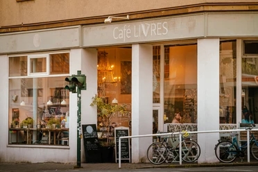 Café Livres, Essen <p>Café mit großen Fenstern, zwei Fahrräder vorne, Speisekarten auf Tafeln, gemütliche Beleuchtung.</p>
