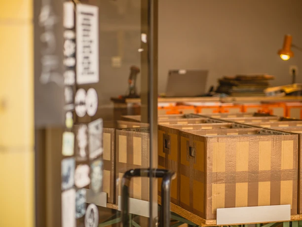 Bahlo Records, Bochum Kartonboxen in einem Lagerraum, durch eine Glastür und beklebt mit Aufklebern sichtbar.