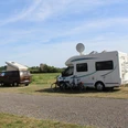 Wohnmobilstellplatz an der Poitou-Eselweide Zwei Wohnmobile stehen auf einer Wiese, mit Fahrrädern und Satellitenschüssel, an einem sonnigen Tag.