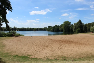 Badesee Lahde Sandstrand am Badesee Lahde mit umgebenem Grün, klarem Himmel und Wolken. Ruhige Wasseroberfläche.