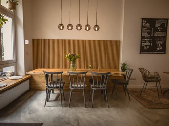 Hi Kalle Cafe, Bochum <p>Gemütliches Café mit Holztisch, buntem Blumenstrauß, modernen Lampen und stilvollen Stühlen.</p>