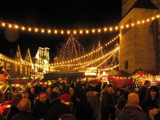 Besucher genießen den festlichen Weihnachtsmarkt mit beleuchteten Ständen und Lichterketten.