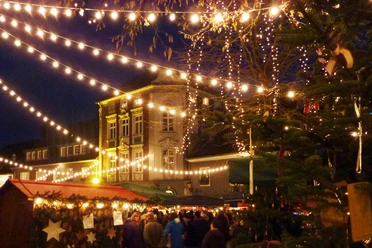 Nächtlicher Weihnachtsmarkt in Mettmann mit festlicher Beleuchtung und einem dekorierten Tannenbaum.