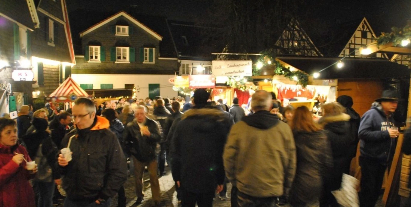 Weinachtsmarkt Wülfrath Titelbild.jpg Nachtaufnahme eines belebten Weihnachtsmarktes in Wülfrath mit zahlreichen Besucher*innen und Lichtern.