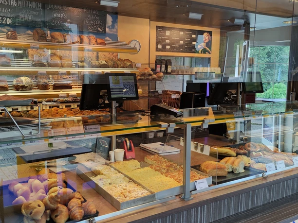 Eine Bäckerei mit umfangreicher Auswahl an Backwaren: Brot, Brötchen, Gebäck hinter einem Tresen.