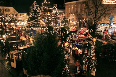 Weihnachtsmarkt in Ratingen bei Nacht aus der Vogelperspektive mit leuchtenden Lichterketten und Buden.