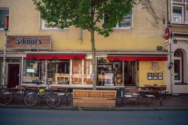 Knut's, Witten <p>Fahrräder und Tische vor einem Café mit rotem Markisendach und gelber Fassade.</p>