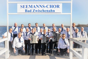 Gruppe des Seemanns-Chors Bad Zwischenahn vor einem See, alle Mitglieder tragen maritime Uniformen.
