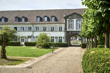 Kloster Saarn, Mülheim an der Ruhr Gebäude mit Arkadenbögen, weißen Fassaden und gepflegtem Grün im Vordergrund.