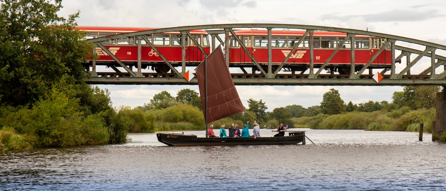 Mit dem Torfkahn auf der Hamme En tørvepram sejler på Hamme foran jernbanebroen, hvor Moorexpress er på vej over.