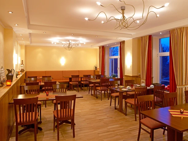 Gesellschaftsraum Möbelei Ein einladender Raum mit dunklen Holzmöbeln, liebevoll dekorierten Tischen und warmem Licht.