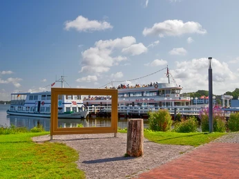 Weisse Flotte Ein großes Ausflugsschiff der „Weissen Flotte“ liegt am sonnigen Anleger. Besucher genießen die Aussicht.