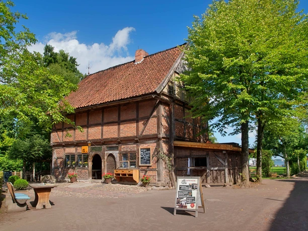 Spieker Ein Fachwerkbau aus Backstein mit rot gedecktem Dach unter blauem Himmel, flankiert von Bäumen.