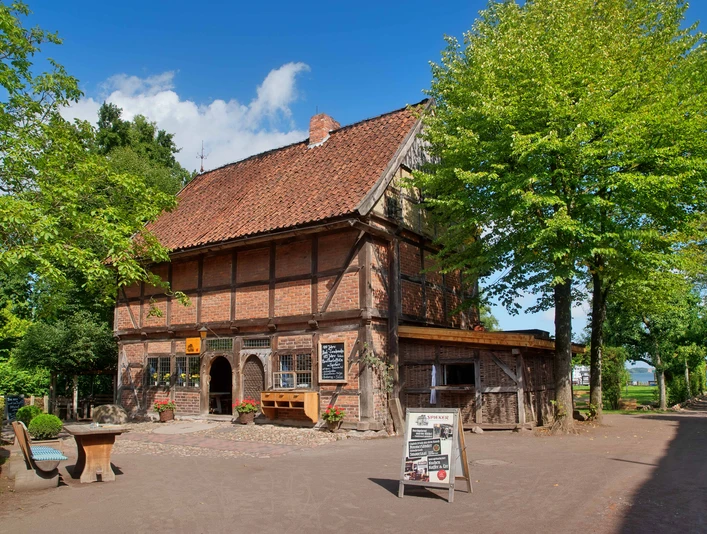 Spieker Ein Fachwerkbau aus Backstein mit rot gedecktem Dach unter blauem Himmel, flankiert von Bäumen.