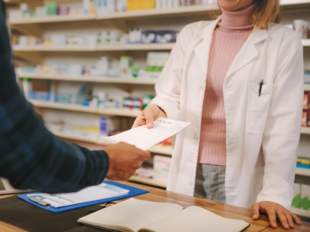 Customer handing over a prescription to the chemist