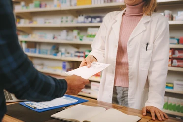Customer handing over a prescription to the chemist Customer handing over a prescription to the chemist