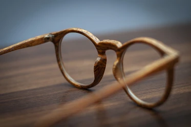 Brille Runde Holzbrille auf Holztisch, Ausdruck von Stil, Nachhaltigkeit und handwerklicher Qualität.