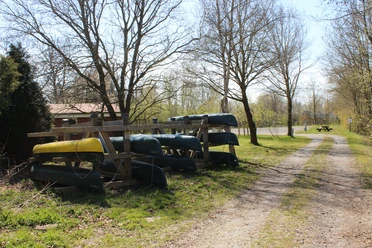 Kanuverleih Ihlienworth Kanus auf einem Holzgestell am sonnigen Feldweg wecken die Vorfreude auf eine Paddeltour.