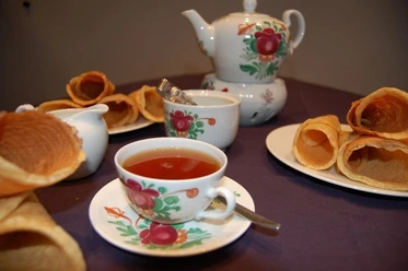 Ostfriesische Teezeremonie Tasse Ostfriesentee mit Kanne und Krintstuut auf Tisch in traditionell bemaltem Porzellanservice