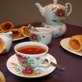Ostfriesische Teezeremonie Tasse Ostfriesentee mit Kanne und Krintstuut auf Tisch in traditionell bemaltem Porzellanservice