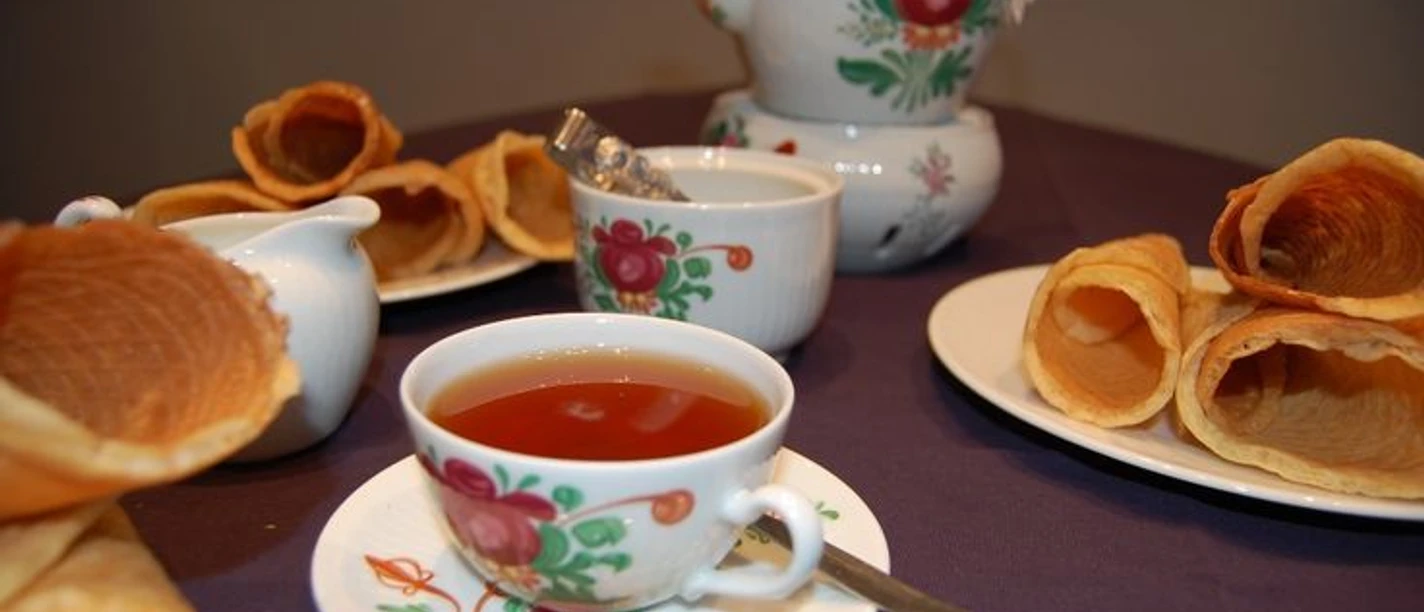 Ostfriesische Teezeremonie Tasse Ostfriesentee mit Kanne und Krintstuut auf Tisch in traditionell bemaltem Porzellanservice