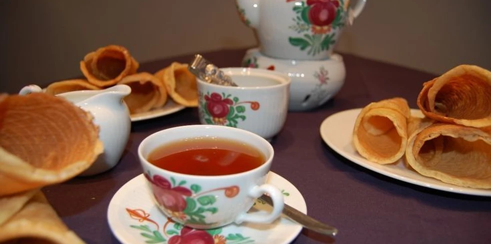 Ostfriesische Teezeremonie Tasse Ostfriesentee mit Kanne und Krintstuut auf Tisch in traditionell bemaltem Porzellanservice