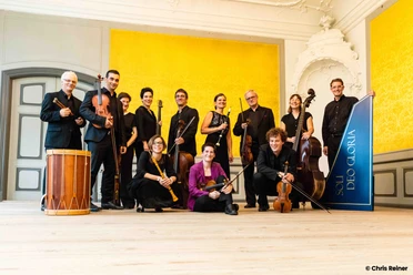 Ein klassisches Musikensemble posiert mit Instrumenten in einem elegant dekorierten Raum.
