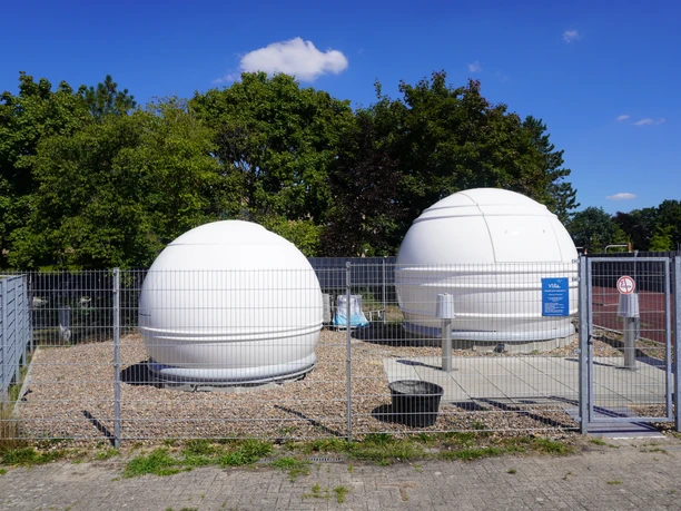 Volkssternwarte Langwedel Zwei weiße Kuppeln einer Sternwarte hinter einem Drahtzaun unter einem klaren blauen Himmel.