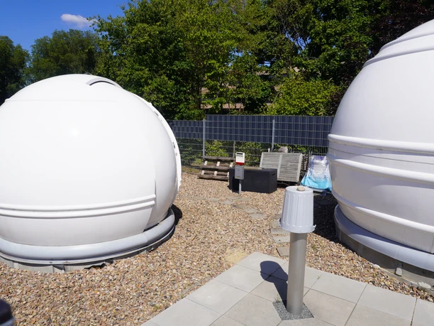 Volkssternwarte Langwedel Kuppler og solpaneler på Langwedel-observatoriet, omgivet af træer i solskin.