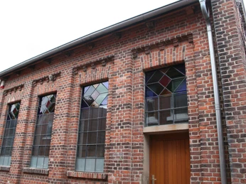 Alte Synagoge Ehemalige Synagoge mit roten Ziegeln und farbigen Glasfenstern, schlichte Architektur und Holzportal.