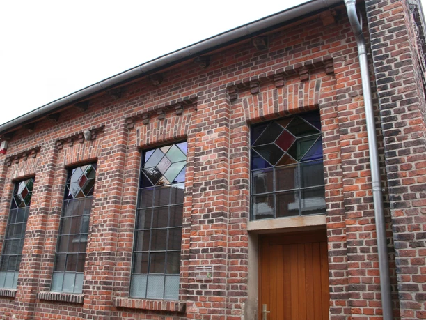 Alte Synagoge Ehemalige Synagoge mit roten Ziegeln und farbigen Glasfenstern, schlichte Architektur und Holzportal.