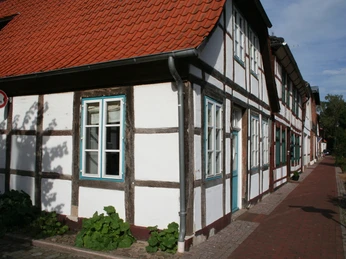 Fachwerkhäuser in Hoya mit weißen Wänden, grünen Fensterrahmen und roten Ziegeldächern.