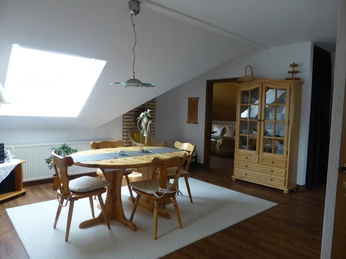 Geräumiges Esszimmer mit vier Kiefernholzstühlen, -tisch, Vitrine und Dachschräge mit Fenster.