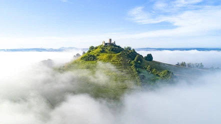 Desenberg im Nebel Die Ruine der Burg Desenberg erhebt sich über einer von Nebel umhüllten, sanften grünen Hügelkuppe.