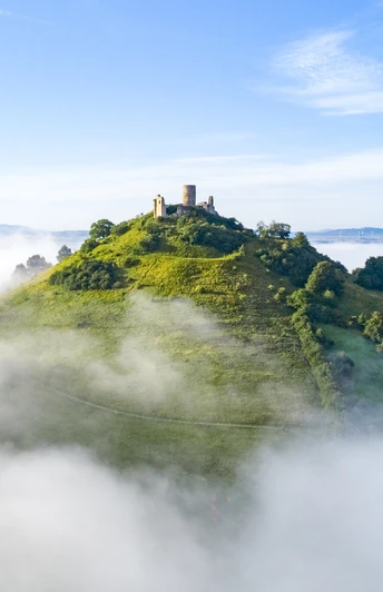 Desenberg im Nebel Die Ruine der Burg Desenberg erhebt sich über einer von Nebel umhüllten, sanften grünen Hügelkuppe.