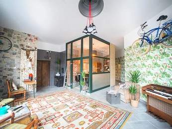 Heller Innenraum eines Aparthotels mit Pflanzen, Vintage-Dekor und hängenden Fahrrädern an den Wänden.