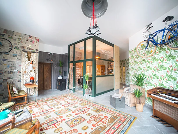 Heller Innenraum eines Aparthotels mit Pflanzen, Vintage-Dekor und hängenden Fahrrädern an den Wänden.