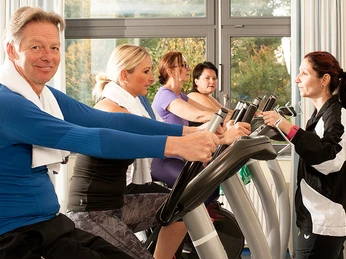 BK_Ergometer_B1000px.jpg Eine Gruppe von Personen trainiert auf Ergometern in einem lichtdurchfluteten Fitnessstudio.