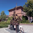 Aper Lieblingsort mit Ritter Herbord Das Bild zeigt eine eindrucksvolle Metallskulptur eines Ritters mit Speer auf einer gepflasterten Fläche vor einem historischen Backsteingebäude. Die Skulptur aus Metallteilen zieht die Blicke auf sich und verleiht dem Platz eine besondere Atmosphäre. Strahlend blauer Himmel und grüne Bäume rahmen die Szene malerisch ein.