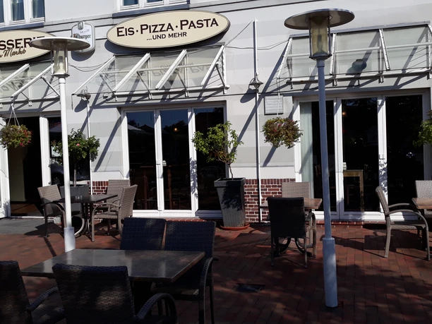 Biergarten Brasserie am Markt Inviting beer garden with green plants, rustic wooden furniture and awnings for shade.