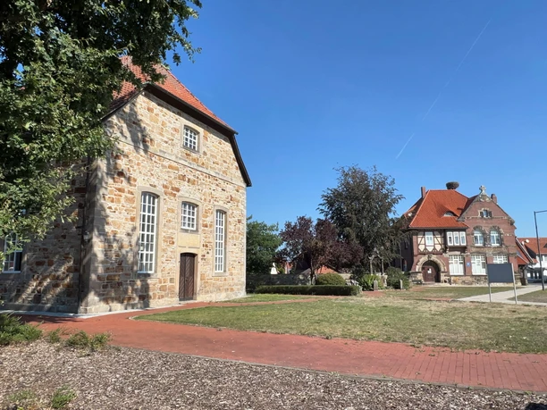 Zwei historische Gebäude in Rehburg, links ein robustes Steinhaus, rechts ein Fachwerkhaus im Hintergrund.