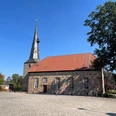 Kirche Rehburg Rehburger Kirche mit markantem Turm, umgeben von Kopfsteinpflaster, sonniger blauer Himmel im Hintergrund.