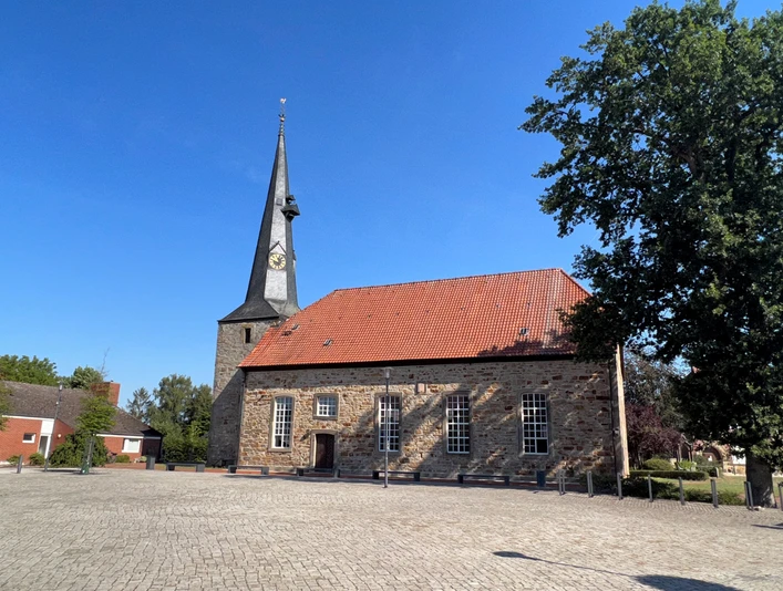 Kirche Rehburg Rehburger Kirche mit markantem Turm, umgeben von Kopfsteinpflaster, sonniger blauer Himmel im Hintergrund.